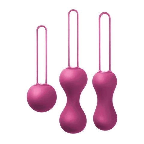 Three magenta-pink kegel balls of increasing size and weight, each with a soft fabric retrieval loop, arranged side by side
